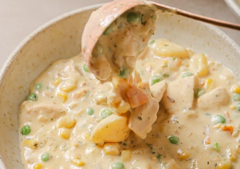 Chicken pot pie soup with peas and carrots in a bowl.