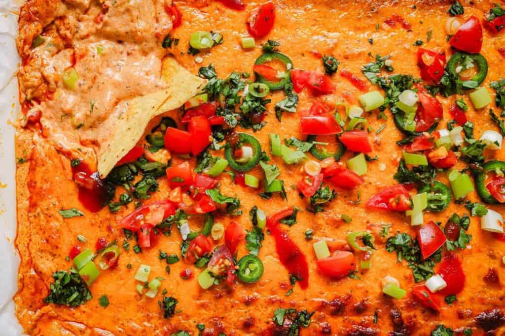 A dish of chili cheese dip in a baking dish with toppings.