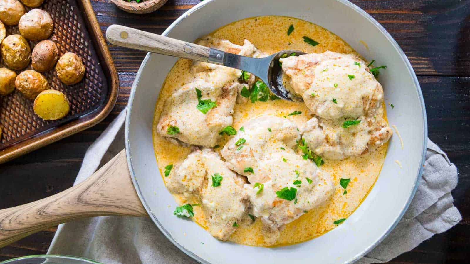 Cream cheese chicken in a white skillet.