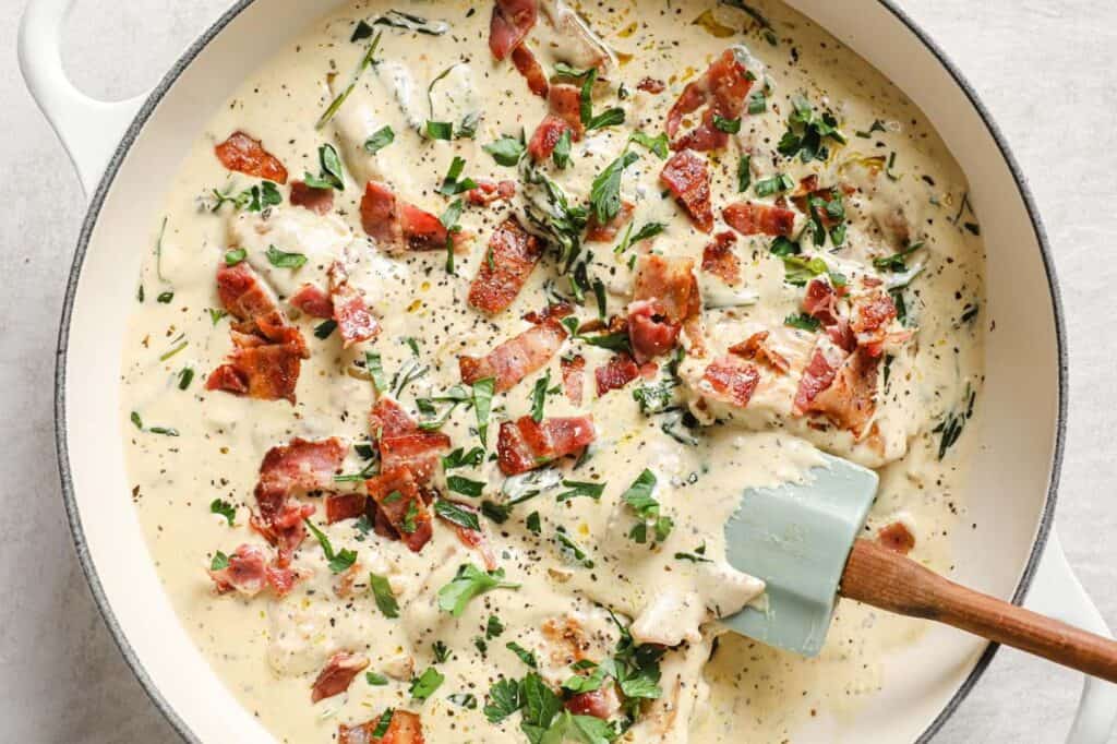 A pan with chicken, spinach and bacon in it.