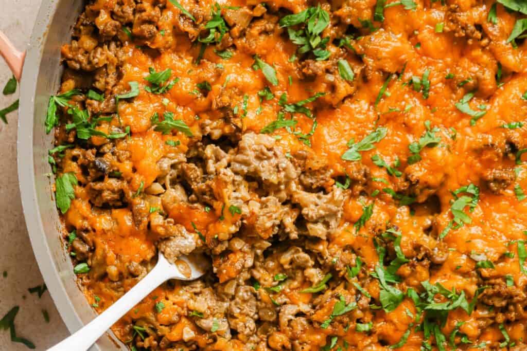 A skillet full of meat and rice with a spoon.