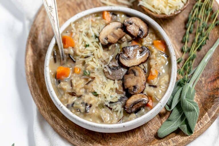 A comforting bowl of wild rice and mushroom soup garnished with sprigs of sage, perfect for cozy winter dinners.