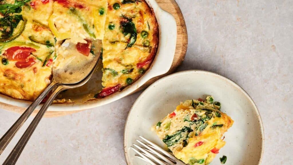 A plate with a slice of quiche and a fork.