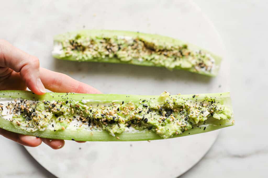 A person holding a cucumber boat over a plate.