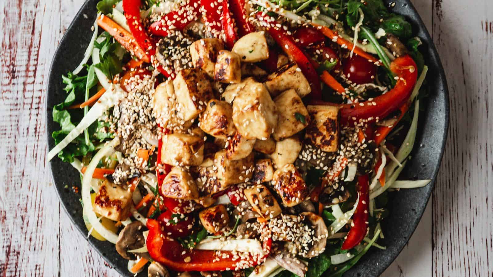 Large plate of fried halloumi salad with wine glass.