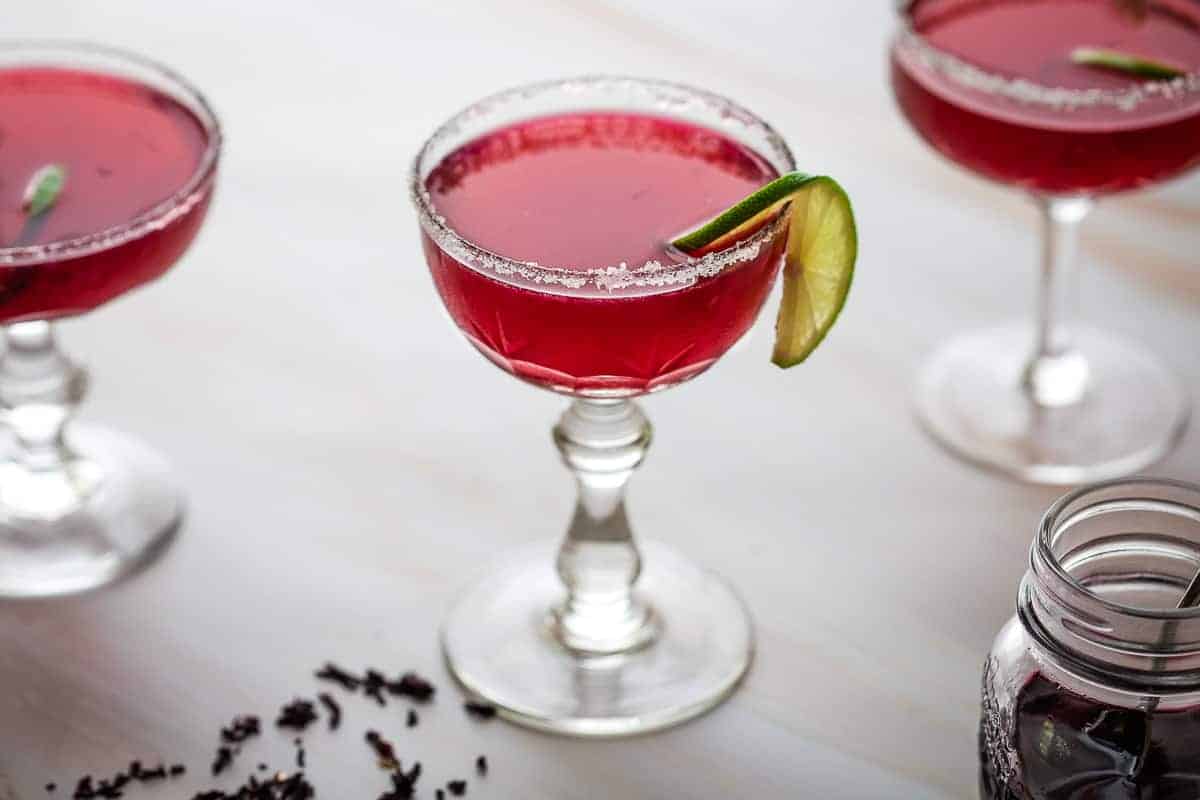 cocktail glass with hibiscus margarita next to two other glasses