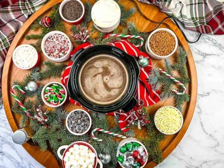 A large platter of hot cocoa, candy, and marshmallows on a table.