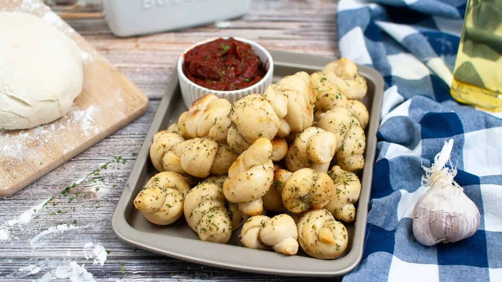 Pan of garlic knots with marinara sauce.