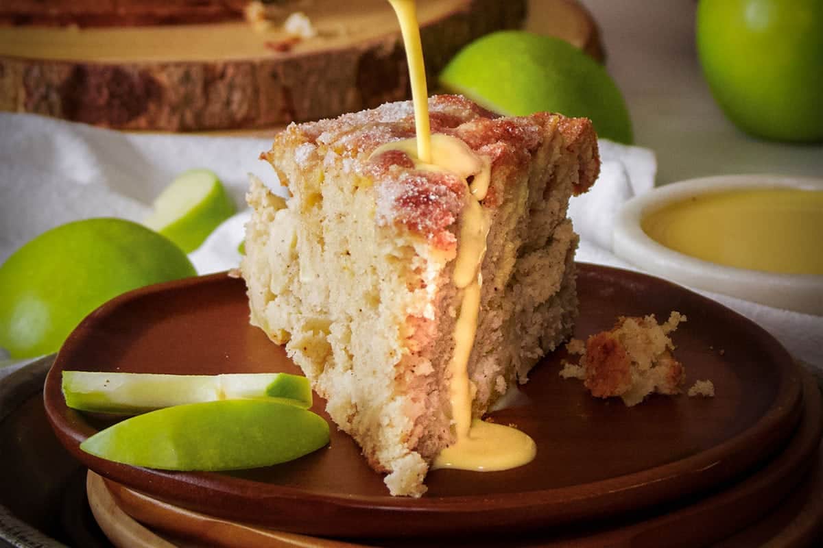 A slice of Irish apple cake is being drizzled with icing.