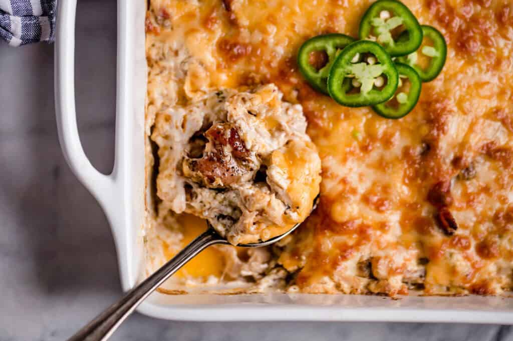 A casserole dish with jalapeño popper chicken and a spoon.