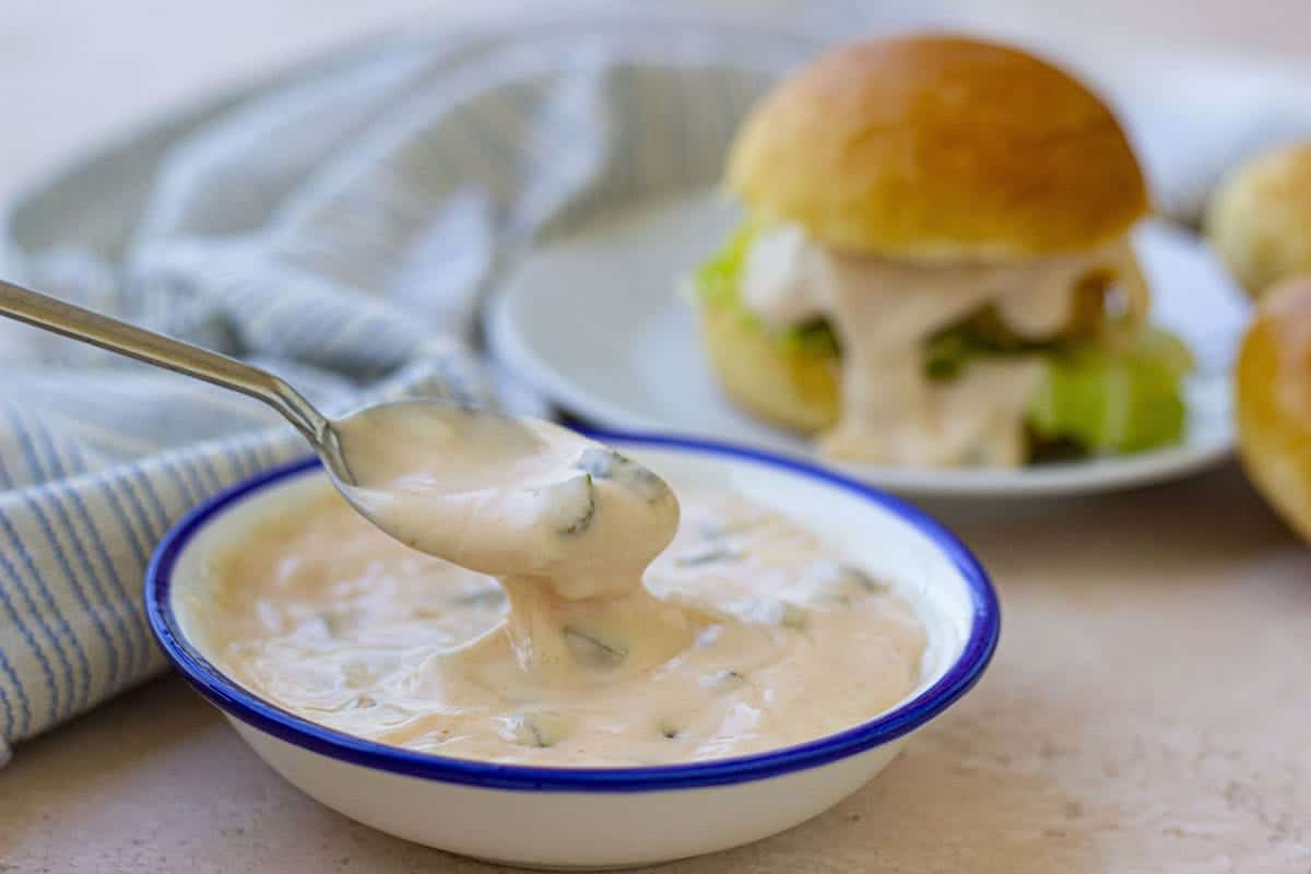 Big Mac sauce in a white plate. Hamburger with sauce in the background.