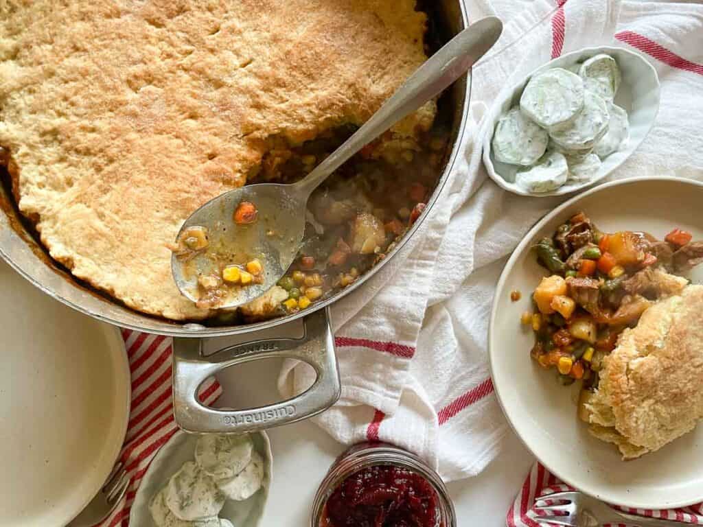 A biscuit topped pie in a skillet with a spoon.