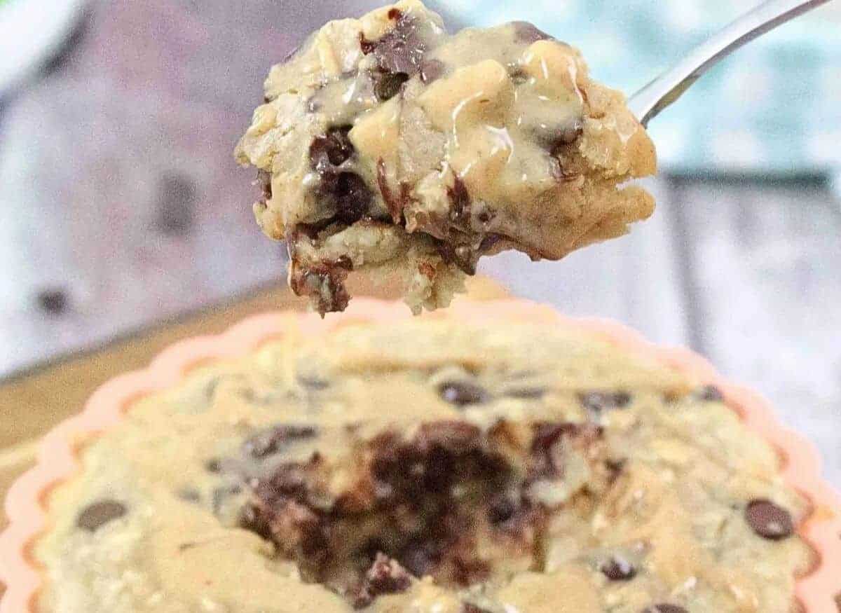 Orange solicone mold on a cutting board with peanut butter chocolate chip baked oatmeal with a spoonful coming out and a blue linen behind it.