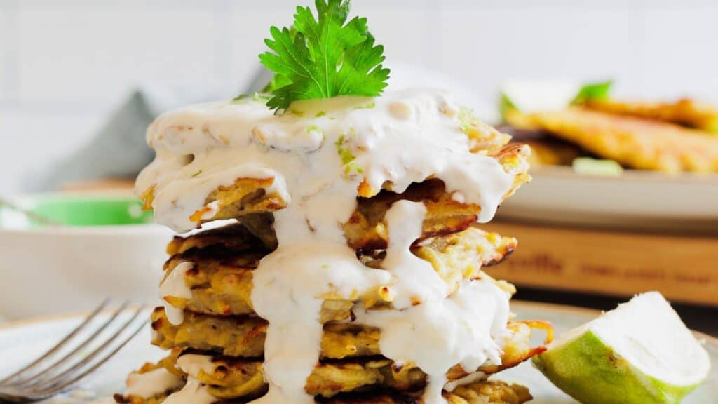 A stack of pancakes on a plate with a lime wedge.