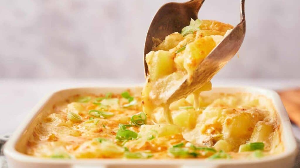 A spoon is being dipped into a casserole dish.