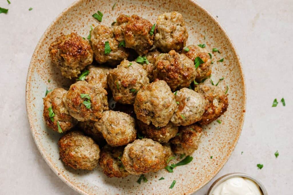 Sausage balls on a plate with a side of dipping sauce.