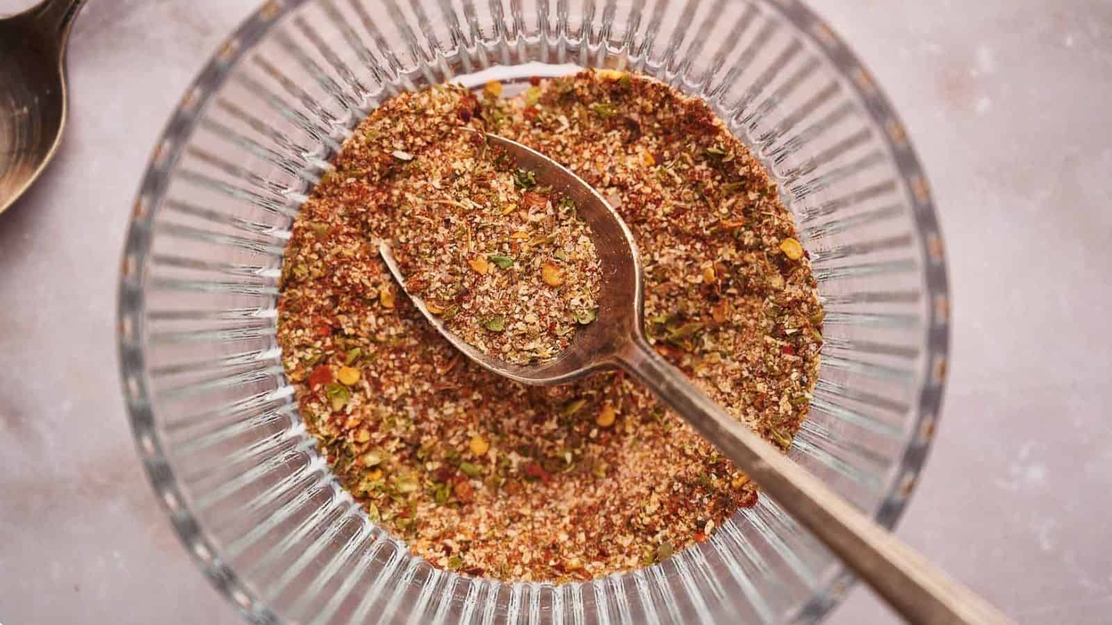 Taco seasoning in a glass bowl with a teaspoon in it.