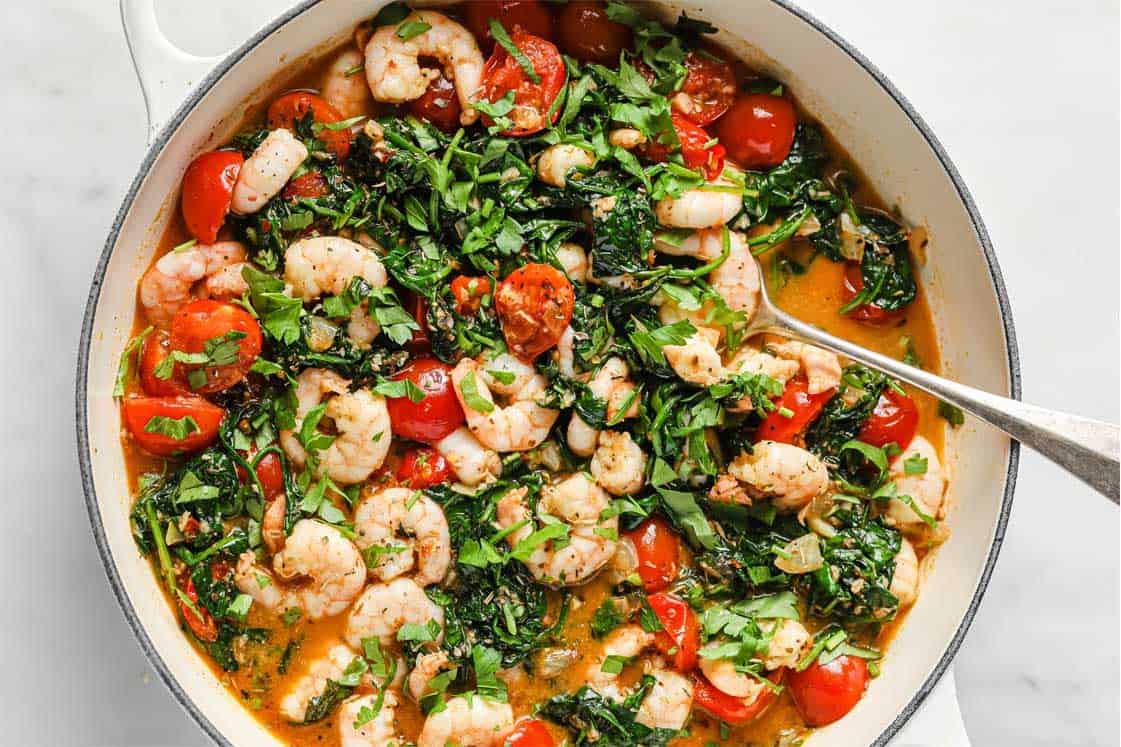 Tuscan garlic shrimp and spinach with tomatoes in a pan.