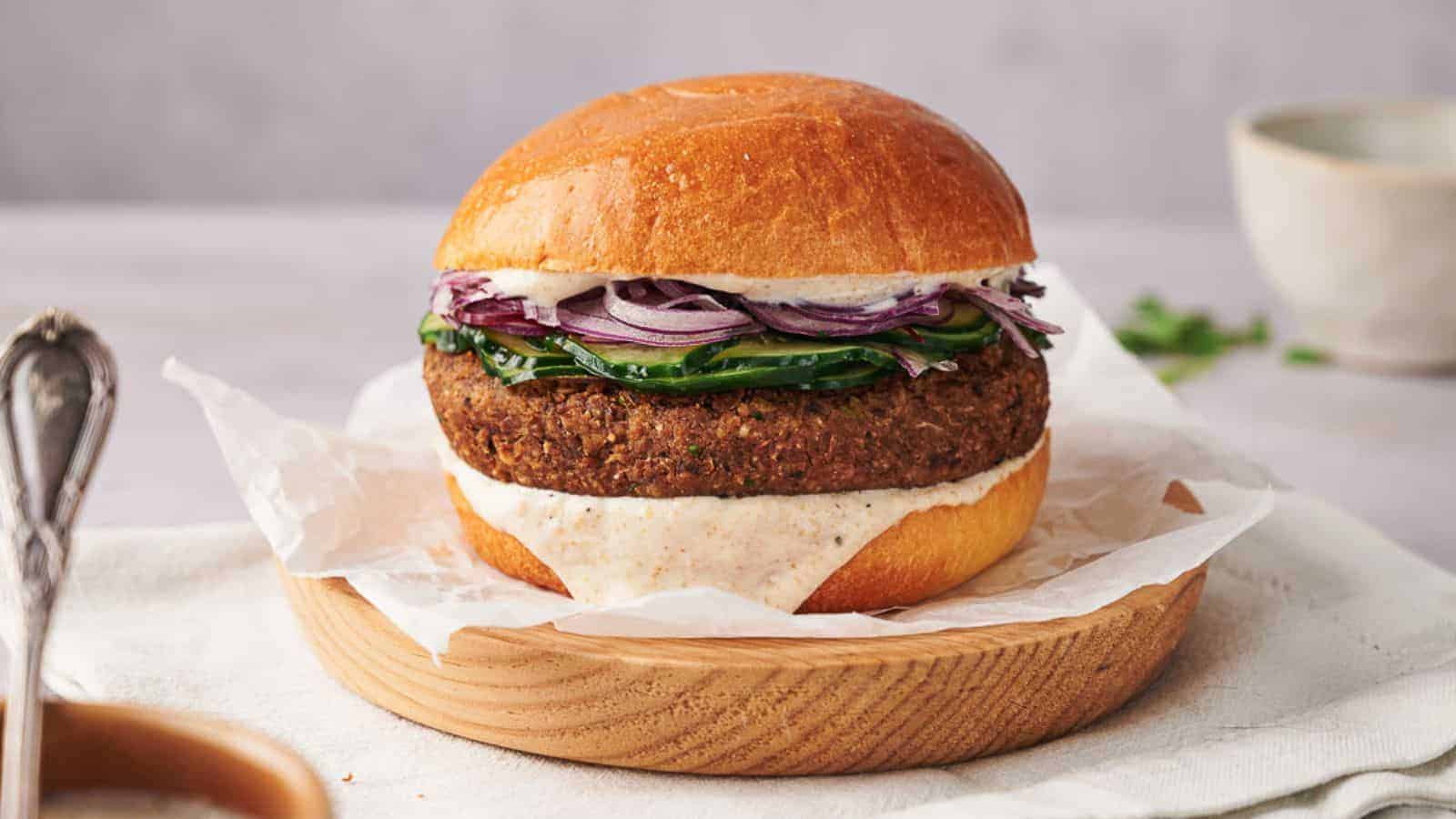 A homemade veggie burger in a bun, on a wooden plate, ready to eat.