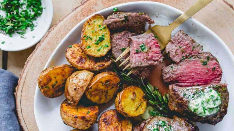 Steak and potatoes on a white plate.