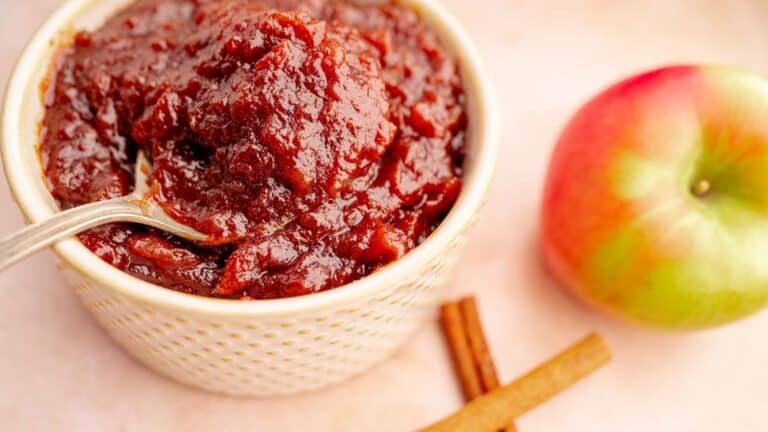 Edible gifts of apple butter in a bowl with cinnamon sticks.