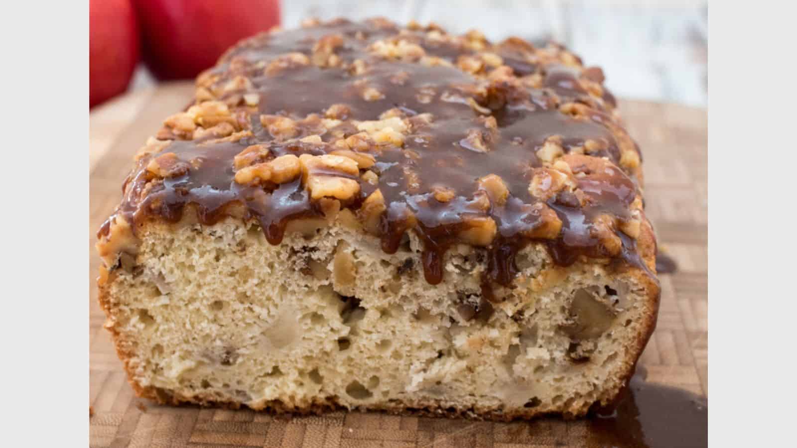 A slice of apple bread with caramel sauce on a cutting board.