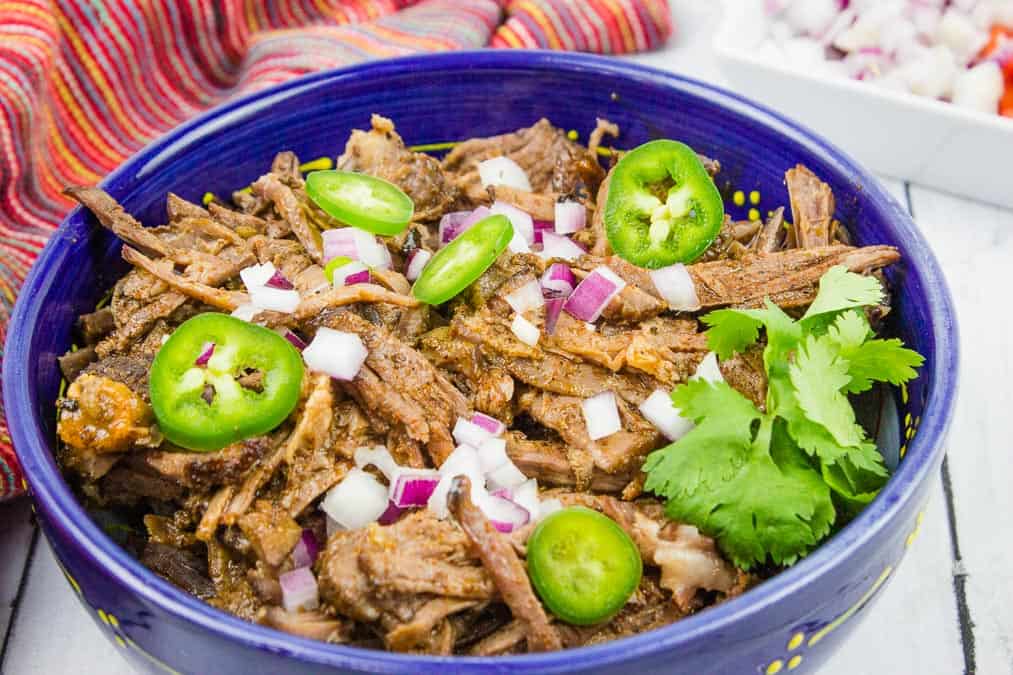 Easy-to-master Mexican beef tacos in a blue bowl with onions and jalapenos.