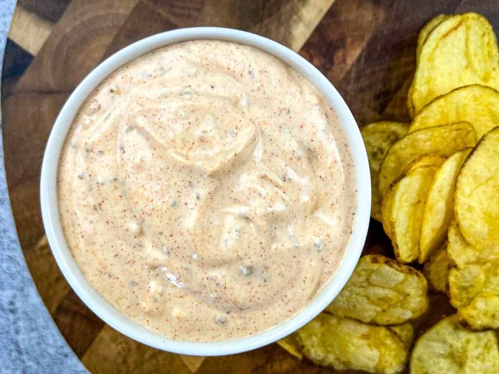 A person dipping a pretzel into a bowl of cajun dip.