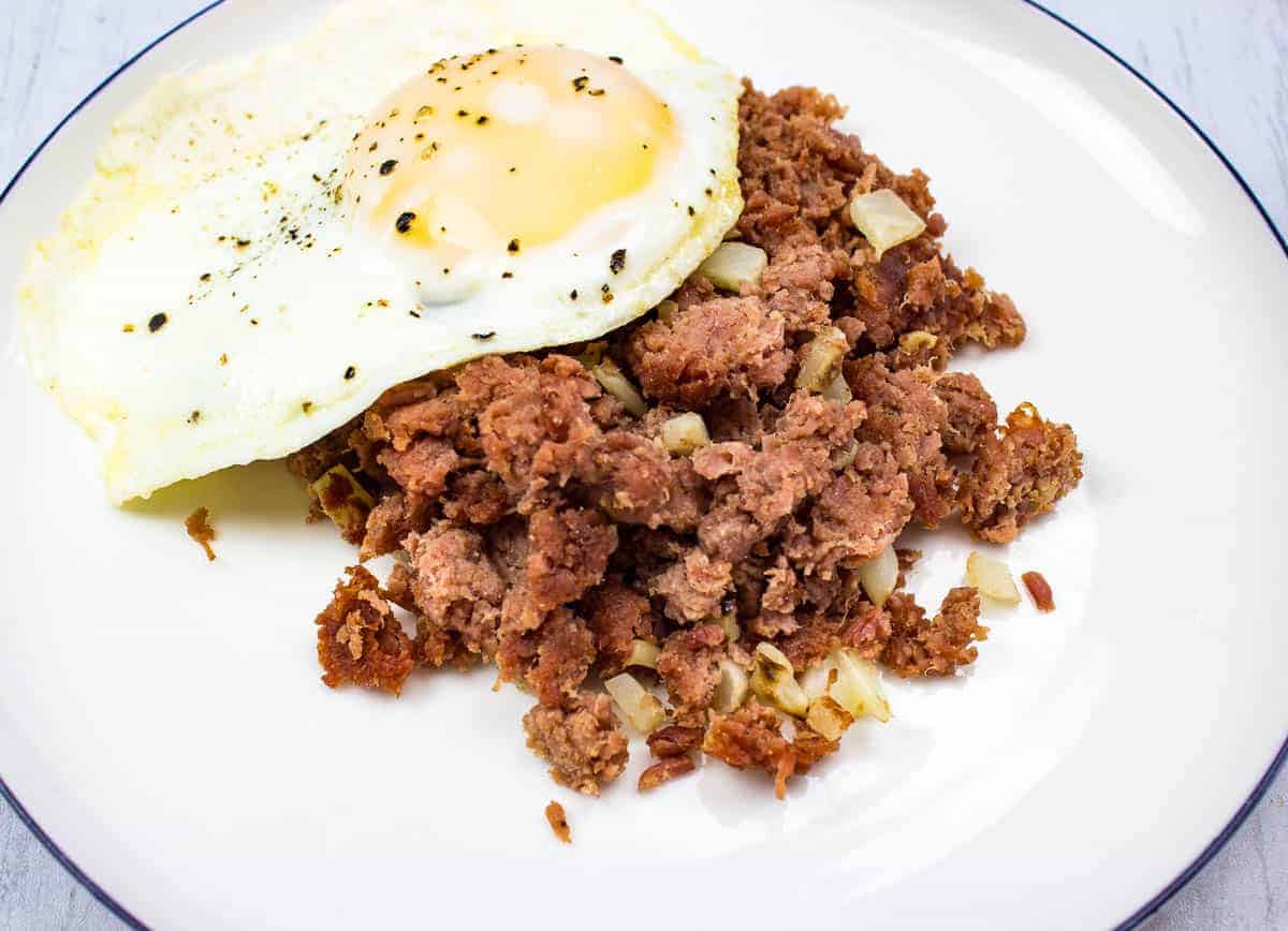 A closeup image of Corned Beef Hash with a fried egg on top.