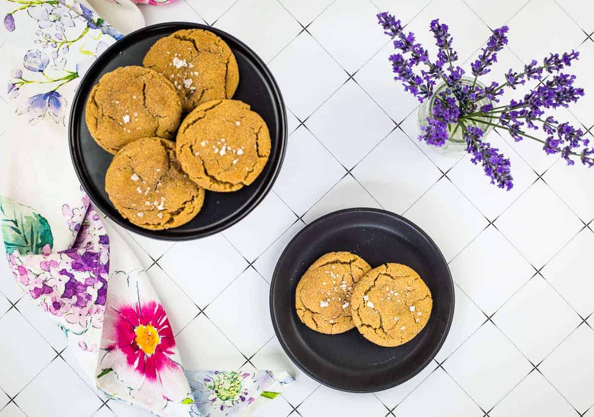 Two bowls of salted caramel snickerdoodle cookies on a plate with lavender flowers on the table.