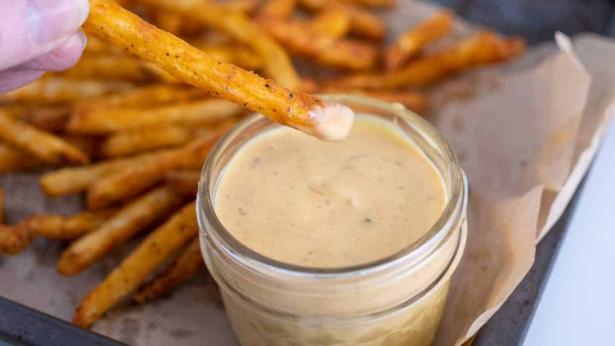 Dipping a French fry into a jar of copycat chick fil a sauce.