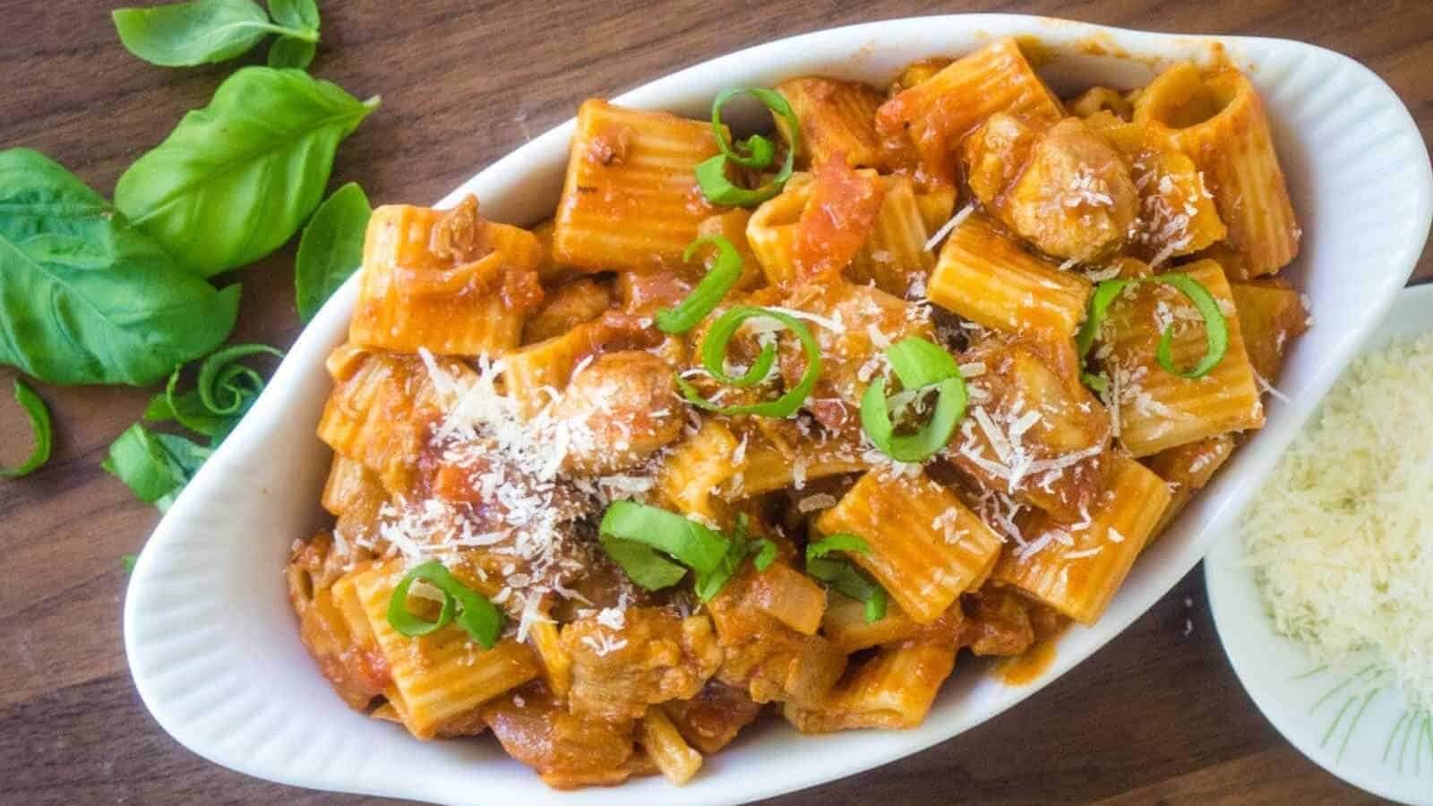 Chicken riggies in a bowl topped with Parmesan and green onion.