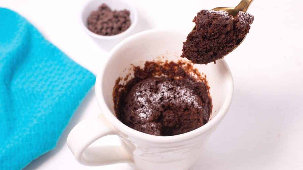 Chocolate mug cake with spoon bite.