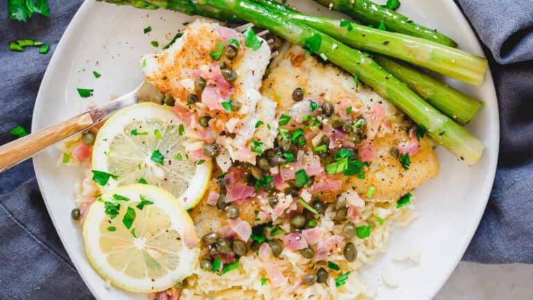 A plate of fish with asparagus and lemon on it.