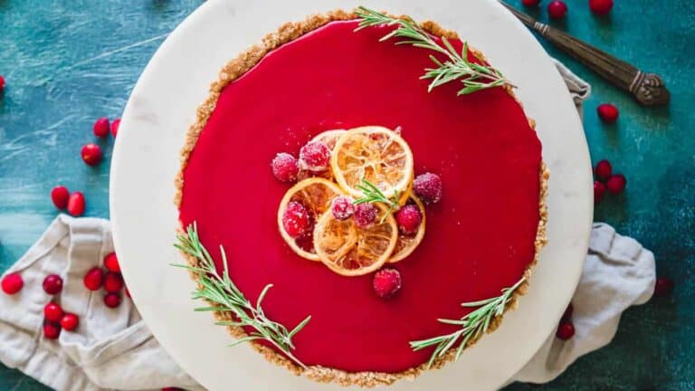 A cranberry tart on a plate with rosemary sprigs.