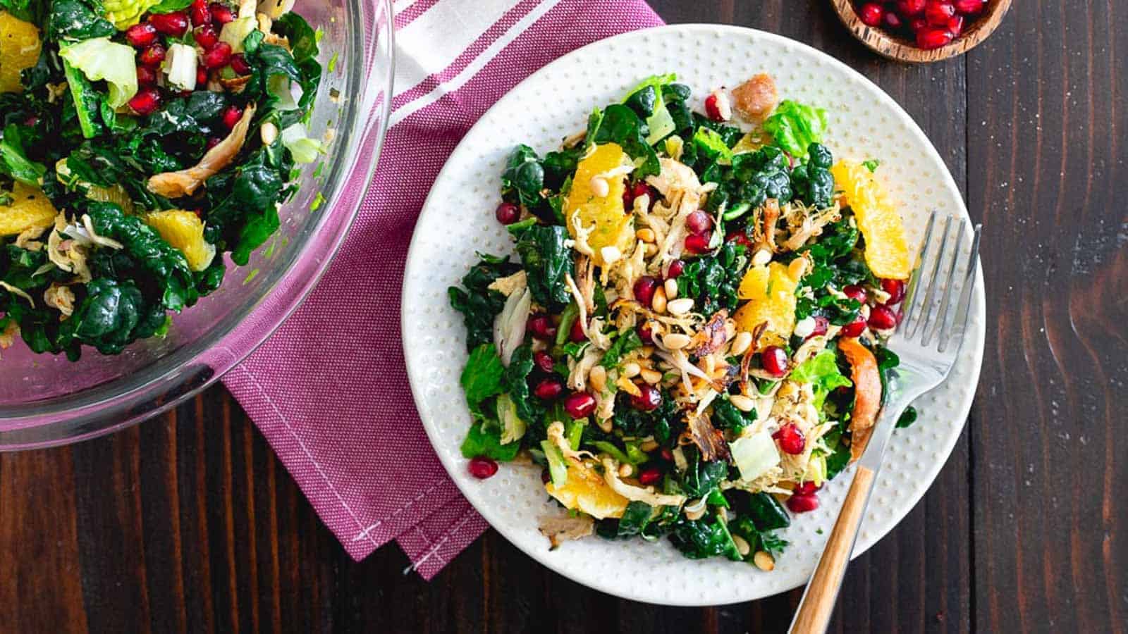 Chopped crispy chicken citrus salad on a white plate with purple kitchen towel.