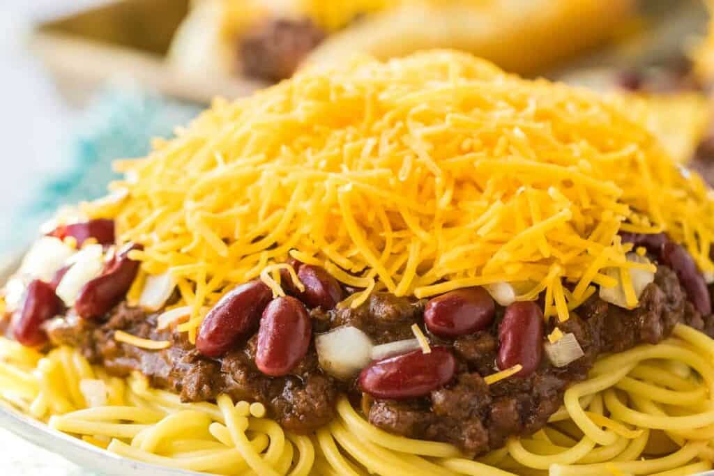 A plate of spaghetti and chili with cheese on top.