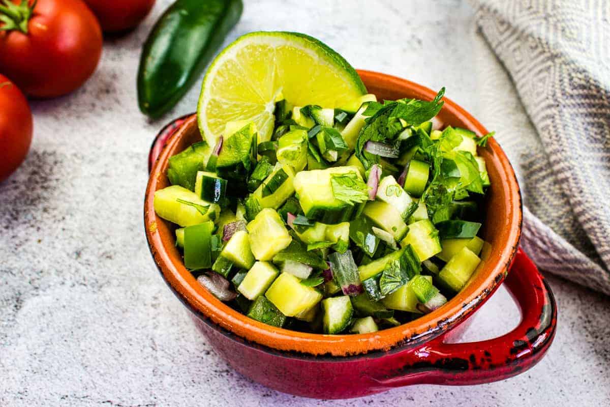 Cucumber salsa in a red bowl.