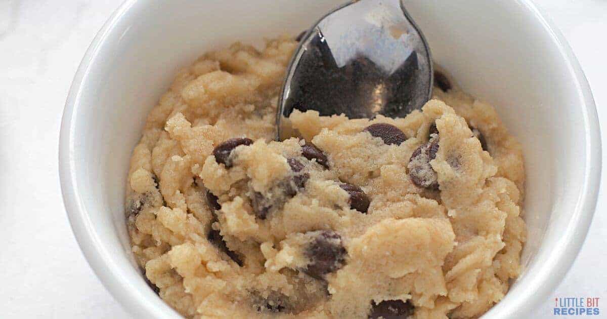 Edible chocolate chip cookie dough in white bowl with spoon.