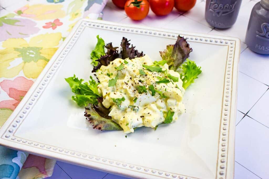 Flavor-packed egg salad on a white plate with tomatoes and lettuce - a delightful and low carb dish.