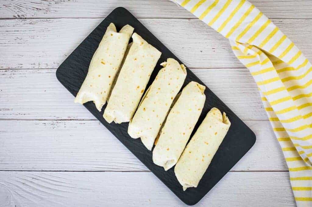 Freezer Breakfast Burritos in a plastic bag on a wooden table.