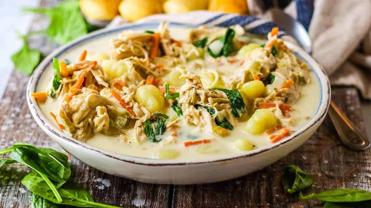 Bowl of copycat Olive Garden chicken gnocchi soup in a bowl with breadsticks in the background.