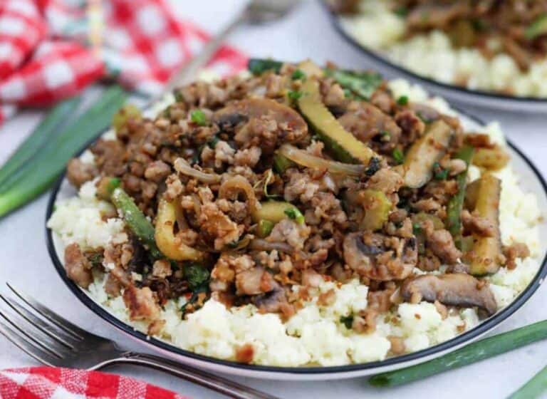 A plate with ground pork and vegetables on top of cauliflower rice.