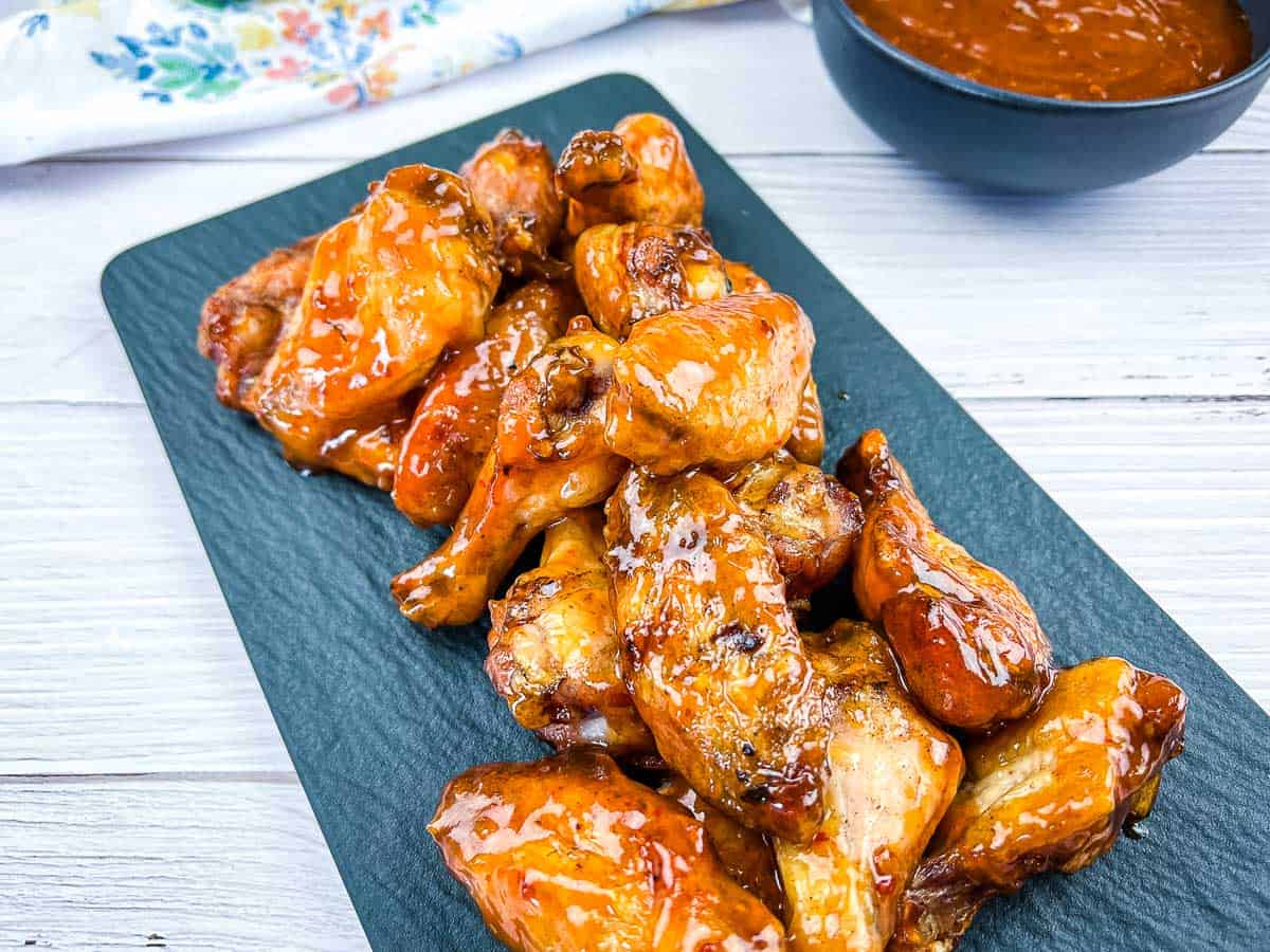 Peach Chipotle Wings on a black plate.