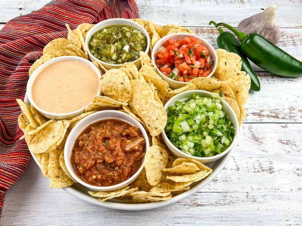 Tomatillo pico de gallo in a black dish surrounded by tortilla chips.