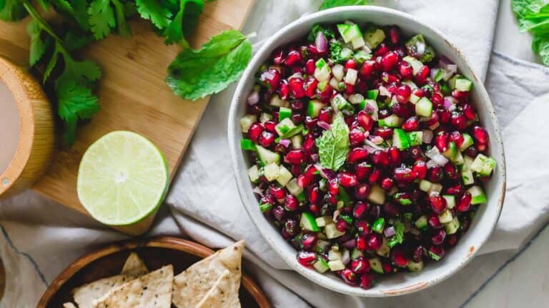 A bowl of pomegranate salsa with lime and tortilla chips.