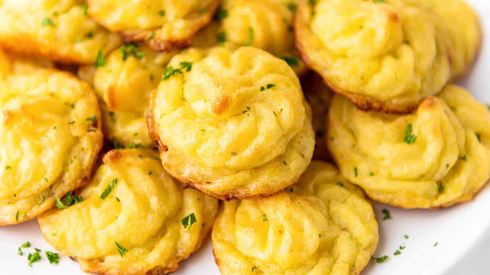 Pommes duchesse on a white plate wiht parsley.