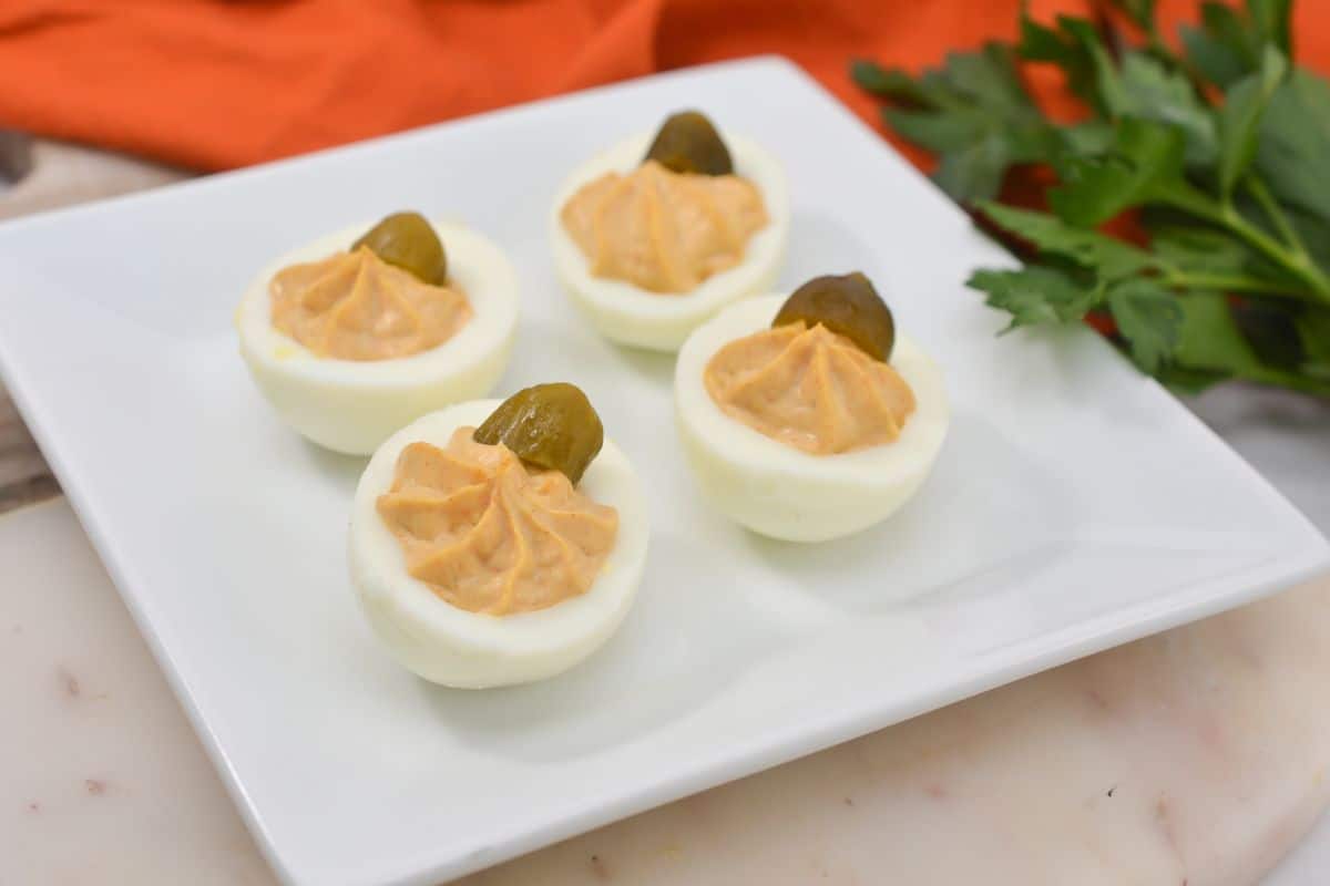 Pumpkin deviled eggs on a white plate.