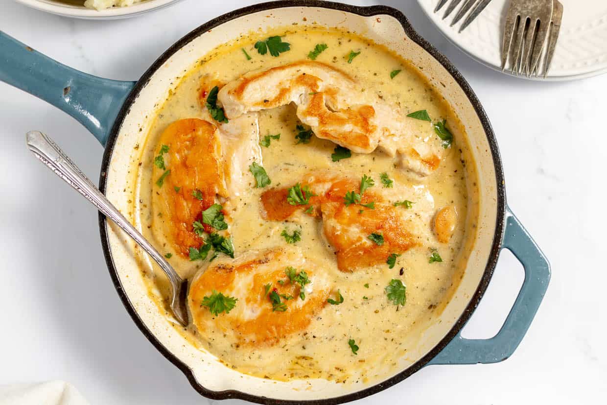 Chicken cutlets in cream sauce in a skillet.