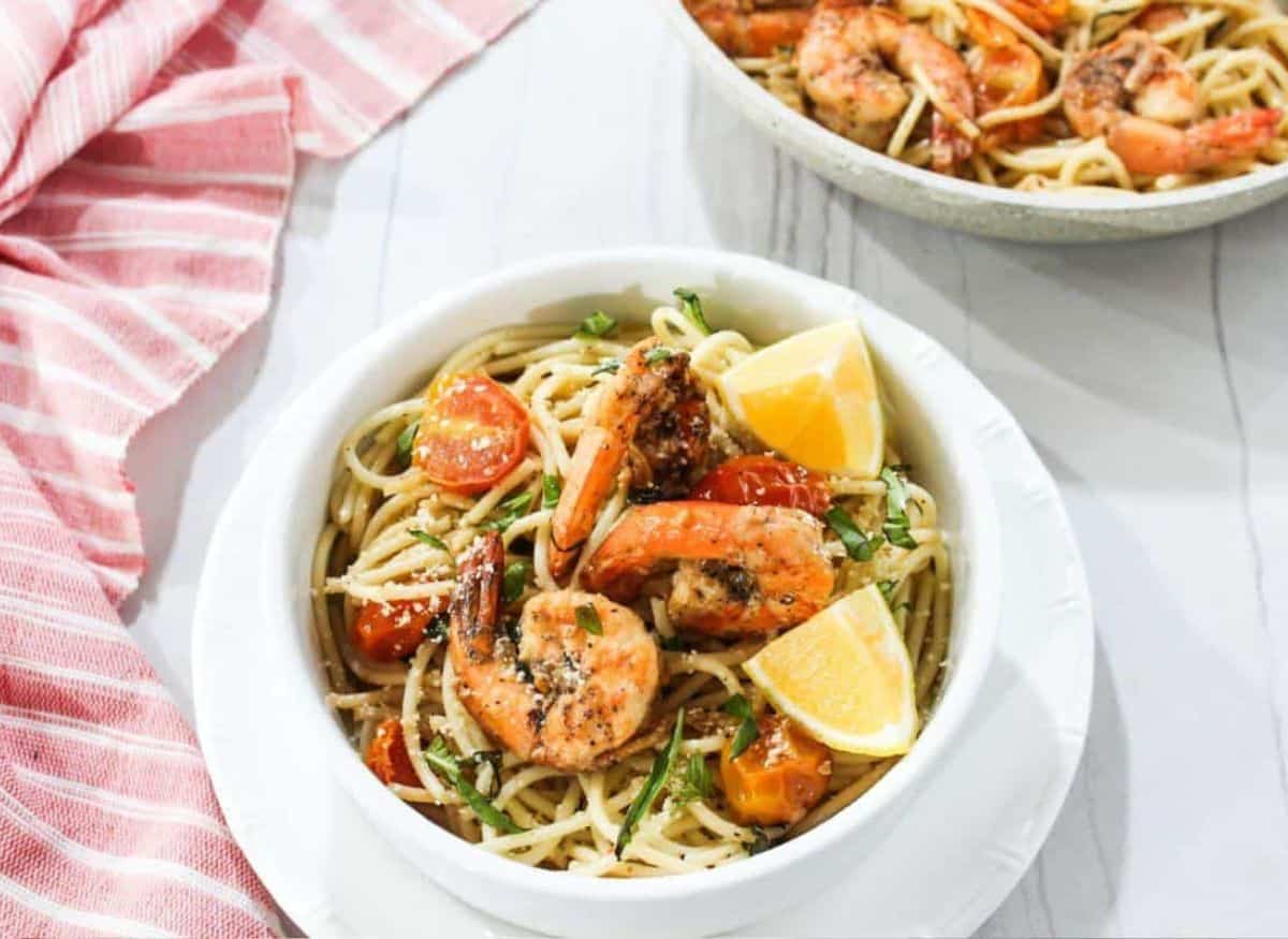 A bowl of pasta with shrimp and tomatoes.